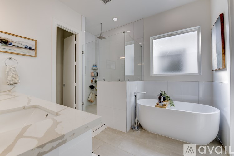 A modern bathroom with a white tub, sink, and shower area.