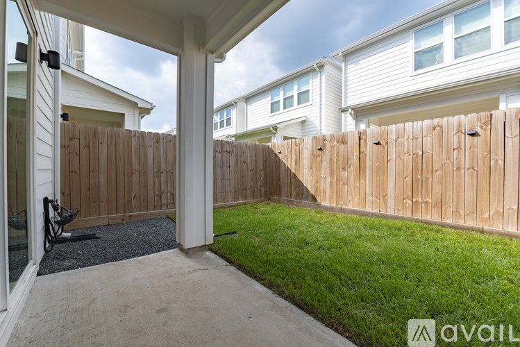 A patio area with a wooden fence and a white house in the background.