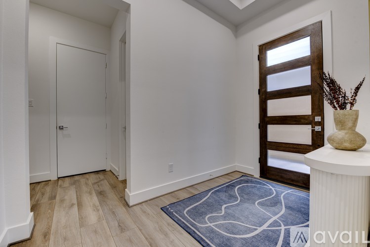 A hallway with a white door, a wooden door, and a blue rug on the floor.