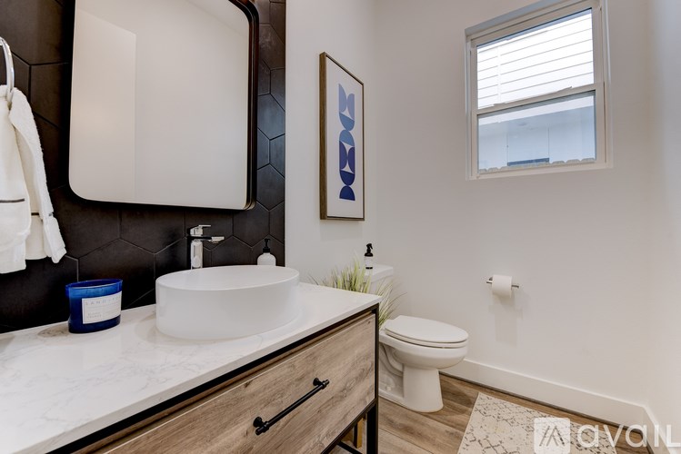 A bathroom with a white sink, toilet, and a window.