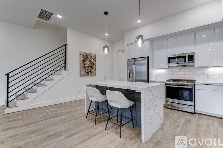 A modern kitchen with a white island and stainless steel appliances.