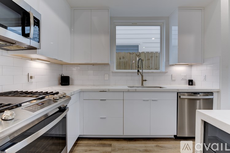 A modern kitchen with white cabinets and stainless steel appliances.