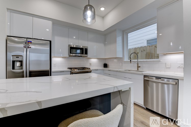 A modern kitchen with a white countertop and stainless steel appliances.