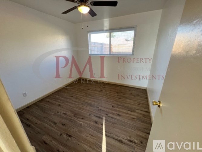 A room with a ceiling fan and wooden flooring, with the text "PMI Property Investments" and "available" on the wall.