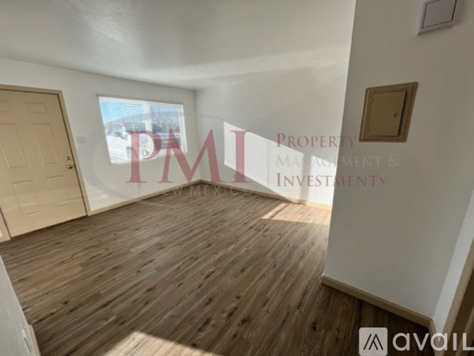 A room with wooden flooring and a window showing a view of a street.