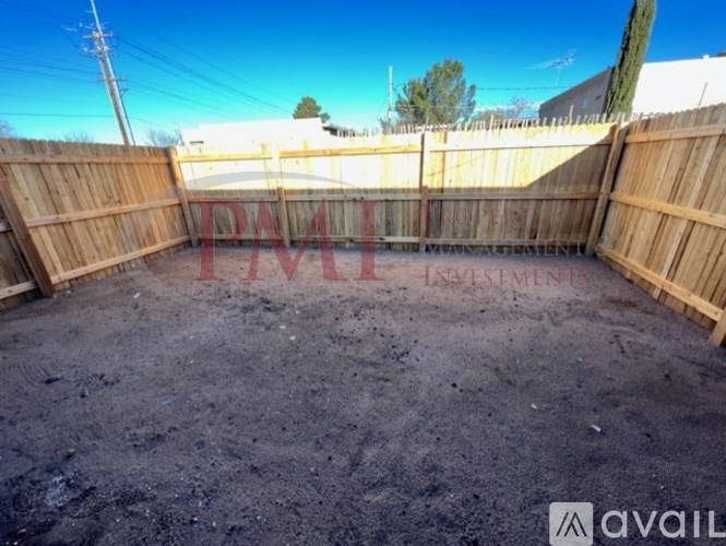 A backyard with a wooden fence and a dirt ground.