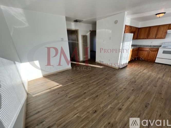 A wooden floor spans the living room and kitchen area of a property for rent.