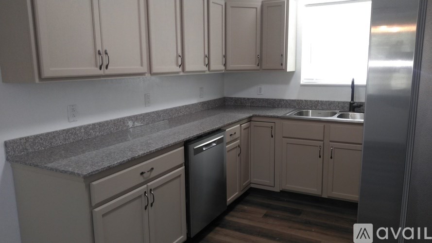 A kitchen with a granite countertop and wooden flooring.