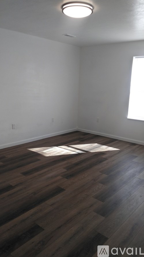 A room with wooden flooring and a window.