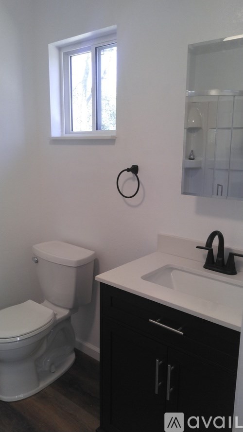 A bathroom with a toilet, sink and a window.