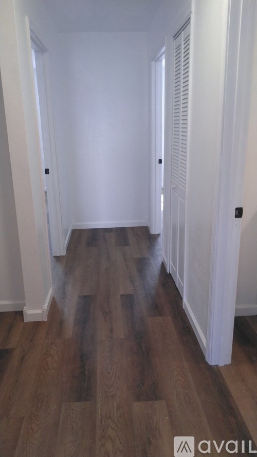 A long hallway with wood floors and white walls.