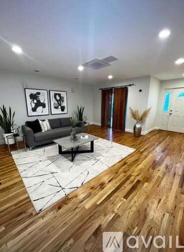 A living room with a grey couch, a coffee table, and a rug with a geometric pattern.
