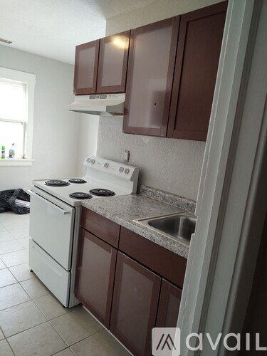 A kitchen with brown cabinets and a white stove top oven.