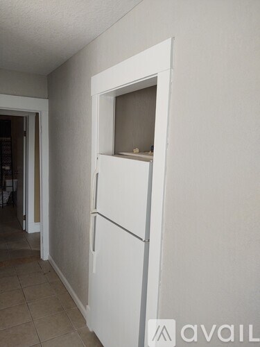 A white fridge in a room with a tiled floor.