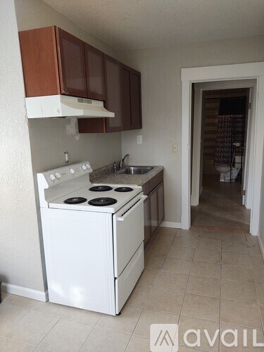 A white stove and sink in a kitchen with brown cabinets.