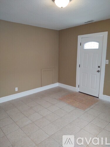 A room with a white door and a tiled floor.