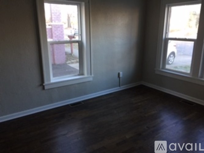 A room with a window and a wooden floor.