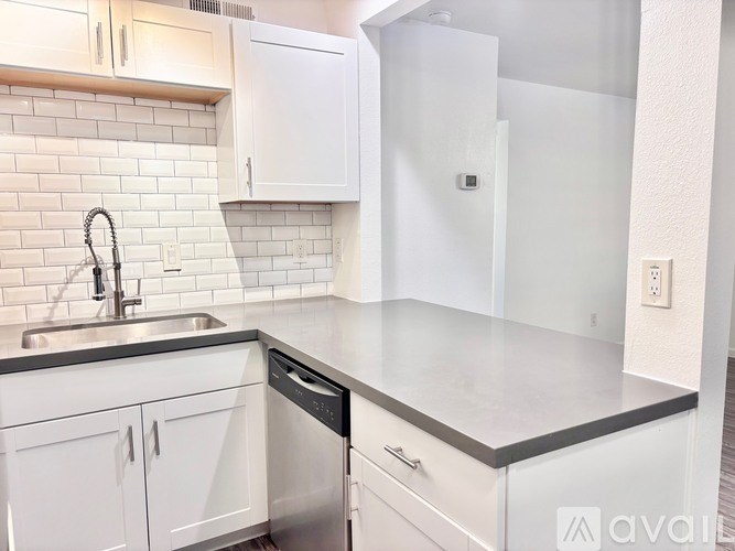 A kitchen with white cabinets and a black dishwasher.