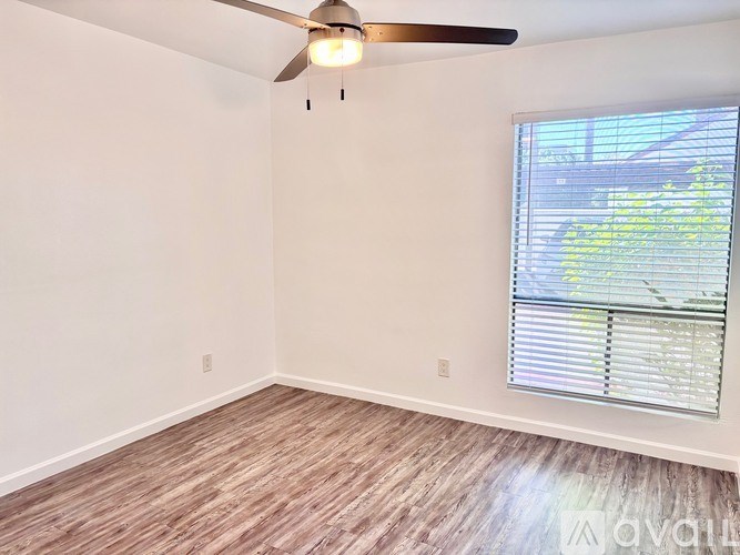 A room with a ceiling fan and a window with blinds.