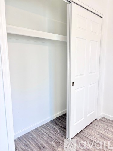 A white door is open to a room with a grey floor.
