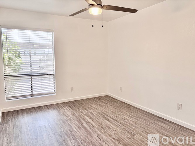 A room with a ceiling fan and a window with blinds.