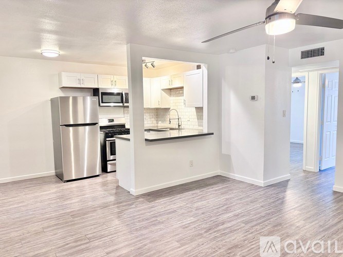 A kitchen with a refrigerator, microwave, oven, and sink.