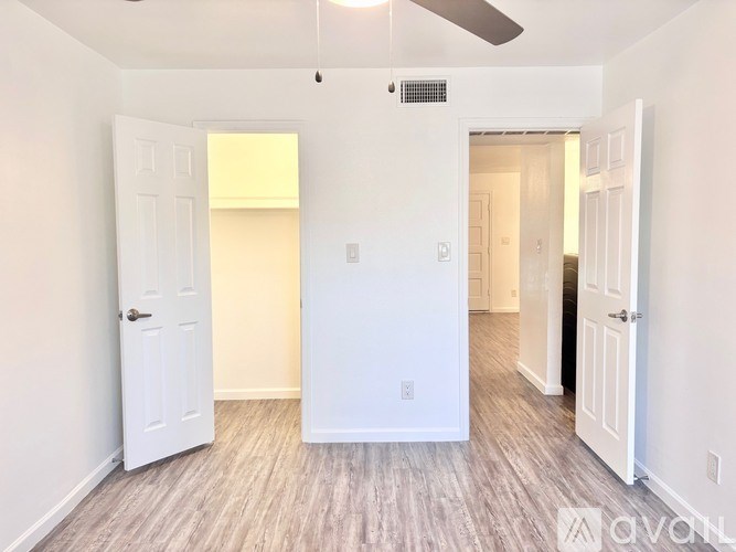 A room with a white door and a ceiling fan.