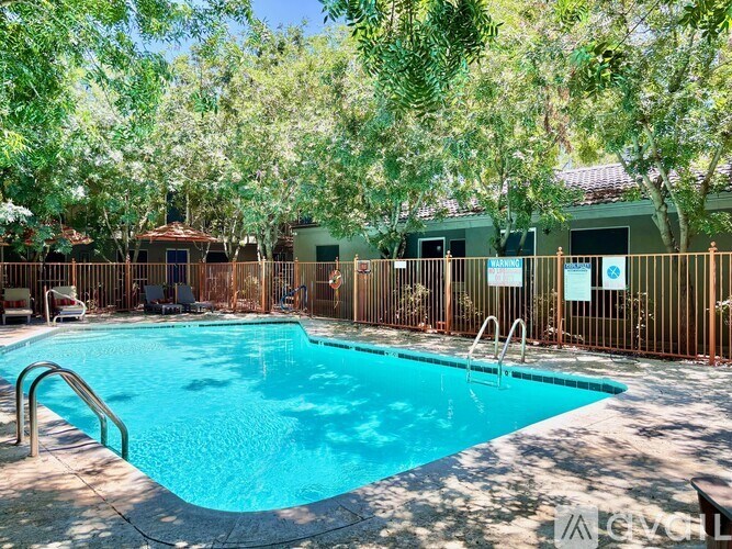 A pool surrounded by trees and a fence.