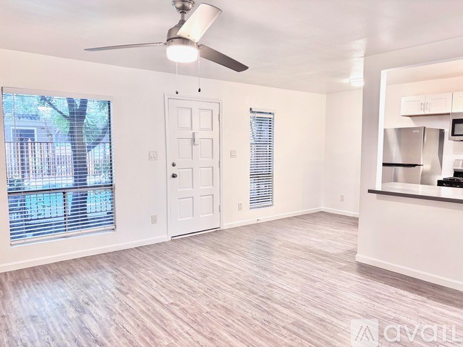 A room with a ceiling fan and light, a door, and a window with blinds.