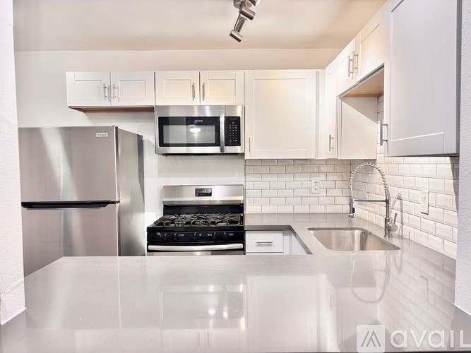 A kitchen with a stainless steel refrigerator, microwave, and oven.