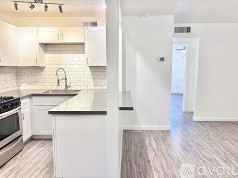 A kitchen with white cabinets and a black countertop.