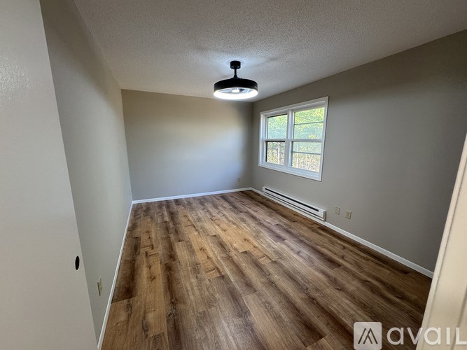 A room with wooden flooring and a window.