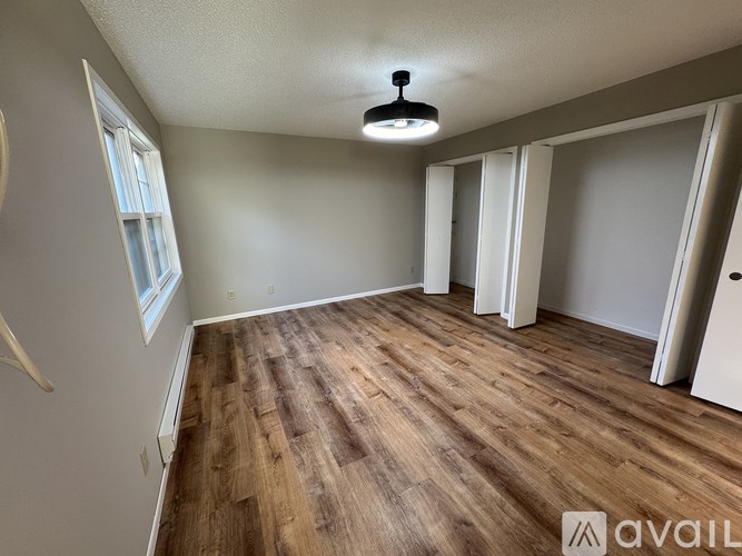 A room with wooden flooring and a window on the left side.