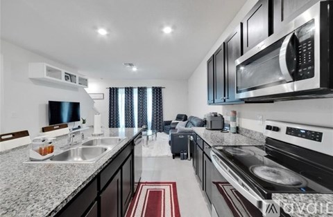 A modern kitchen with black cabinets and stainless steel appliances.