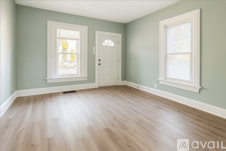 A room with light green walls, a white door, and a window with blinds.