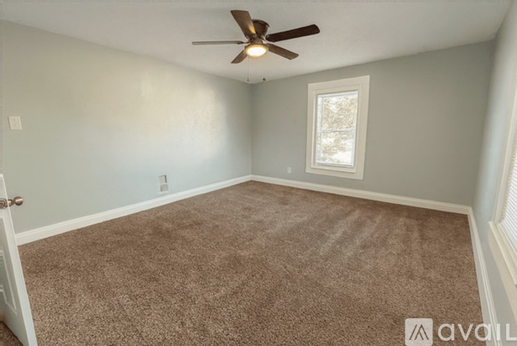 A room with a ceiling fan and carpeted floor.