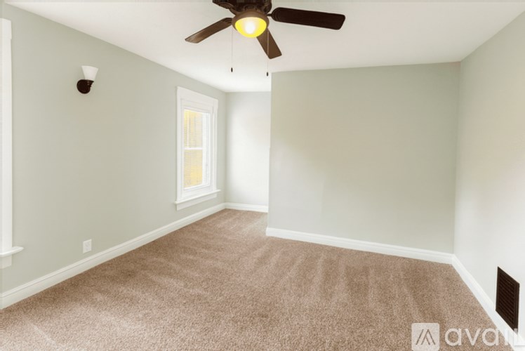 A room with a ceiling fan and carpeted floor.