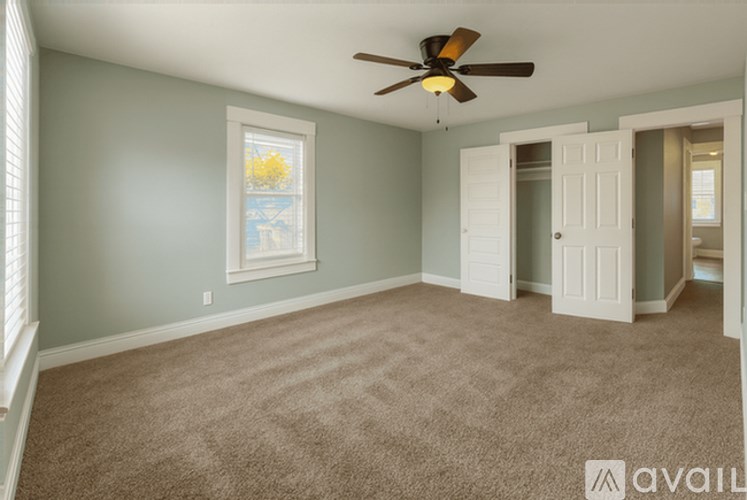 A room with a ceiling fan and a window with a view of a body of water.