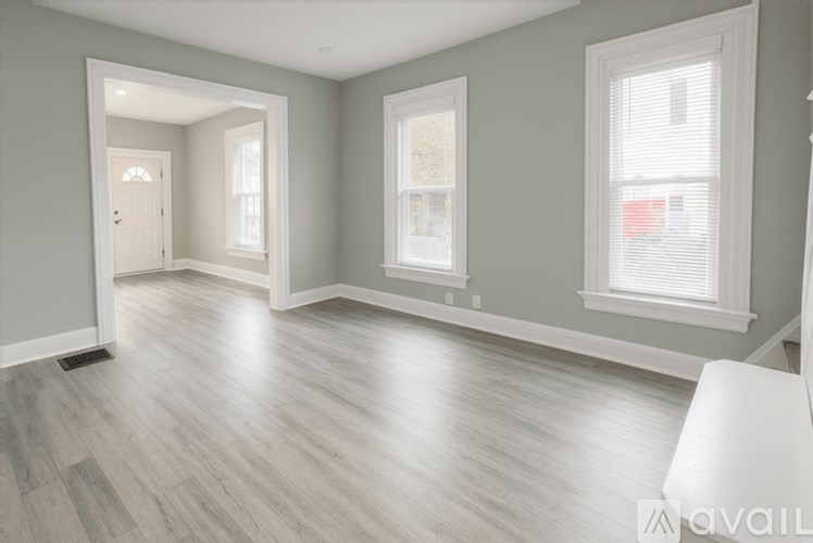 A spacious room with light grey walls and wooden flooring.