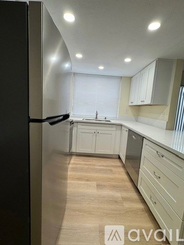 A kitchen with white cabinets and a black refrigerator.