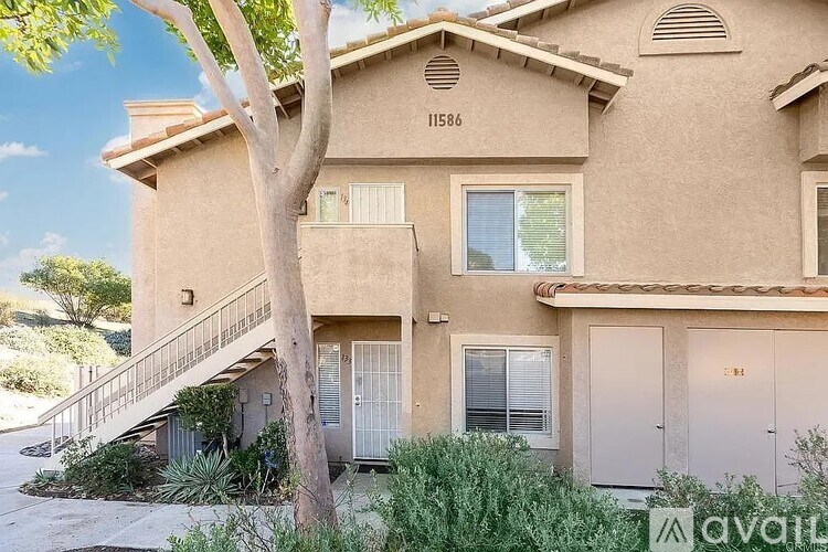 A beige house with a tree in front of it.