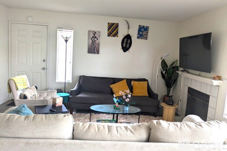 A living room with a white couch, a grey couch, a coffee table, and a fireplace.