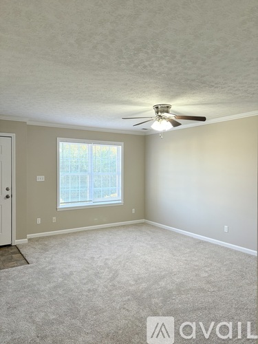 A room with a carpeted floor, a ceiling fan, and a window.