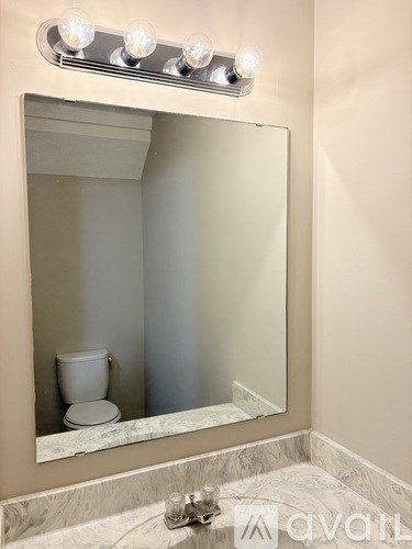 A bathroom with a mirror, a toilet and a sink.