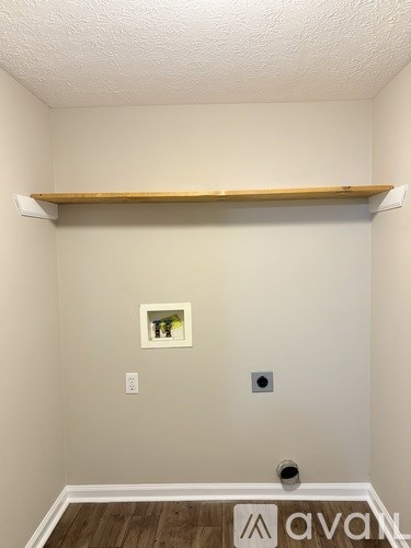 A room with a wooden shelf and a picture on the wall.