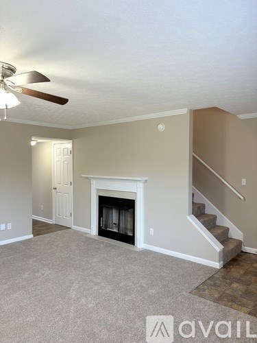 A living room with a fireplace and stairs leading to the second floor.