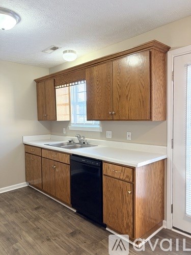 A kitchen with wooden cabinets and a black dishwasher.