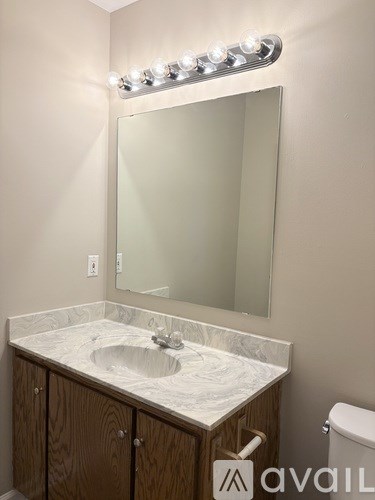 A bathroom with a sink, mirror, and toilet.