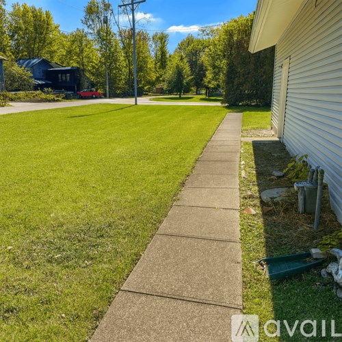 A sidewalk runs alongside a grassy area in front of a house.