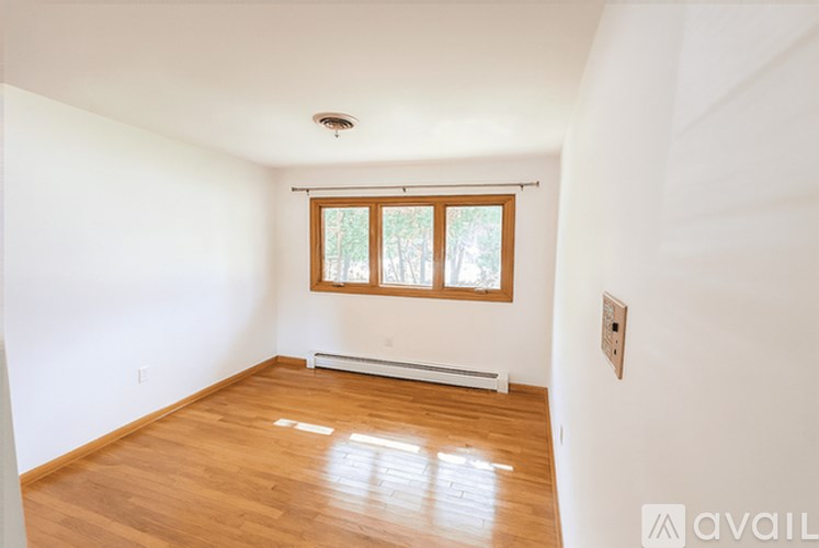A room with wooden floors and a window with blinds.